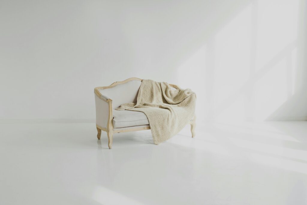 A beige throw on a vintage white sofa in a bright minimalist living space.