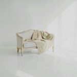 A beige throw on a vintage white sofa in a bright minimalist living space.